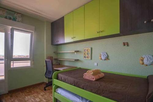 Un dormitorio con una cama con paredes verdes y una ventana en El Campus de Zamora, en Zamora