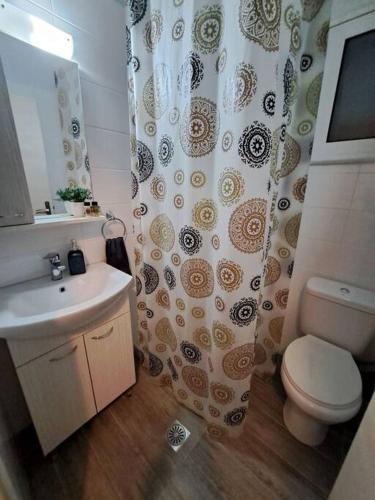 a bathroom with a sink and a toilet and a shower curtain at Lydia's cozy house in Paradeísion