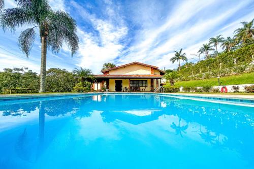 ein großer blauer Pool vor einem Haus in der Unterkunft Casa de campo c piscina e natureza em Mairinque SP in Mairinque