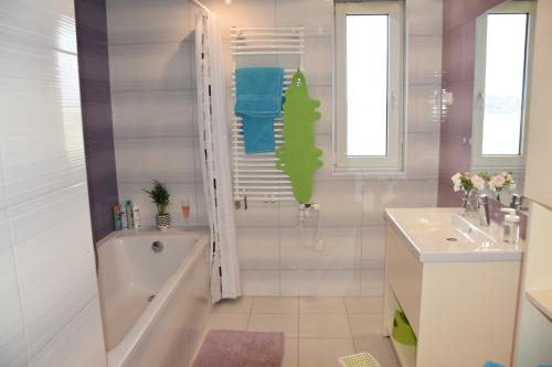 Baño blanco con bañera y lavamanos en Panorama Apartman en Velence