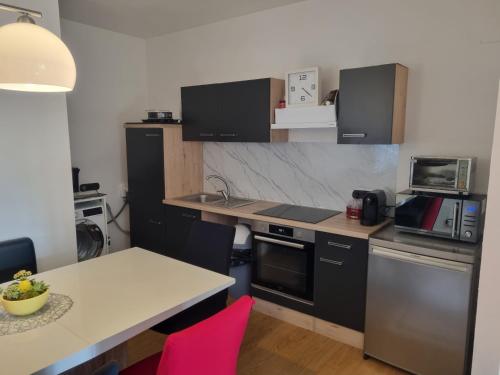 a kitchen with black cabinets and a table with pink chairs at TWO Self-Check-In, 3km freeway, Free-Parking Playstation in Wolfpassing an der Hochleithen