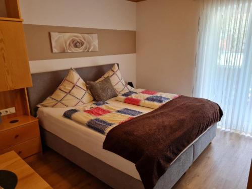 1 dormitorio con cama con edredón y almohadas en Gästehaus Lehr, en Kinding