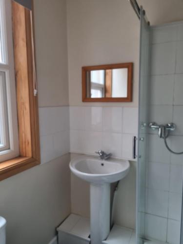 a white bathroom with a sink and a shower at Leeds House Guest House in Bridlington