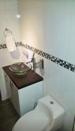 La salle de bains blanche est pourvue de toilettes et d'un lavabo. dans l'établissement ApartHotel moderno y céntrico por la Av. Dolores, à La Pampilla