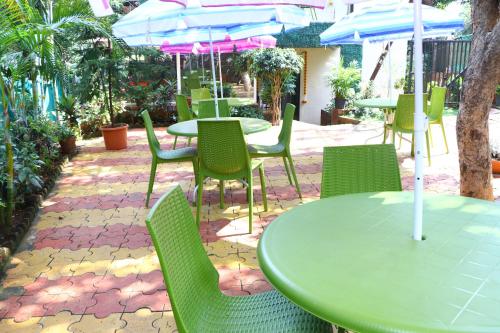 a green table and chairs with umbrellas on a patio at Neuaura Stays in Mahabaleshwar