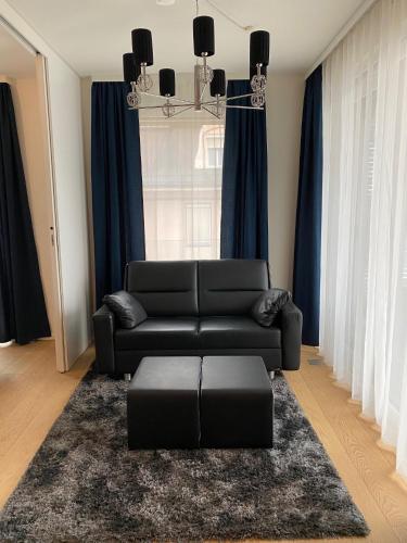 a living room with a black couch and a rug at See & You Ferienwohnung mit Hotelanbindung in Pörtschach am Wörthersee