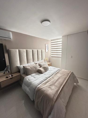a white bedroom with a large bed with a headboard at Apartamento Amoblado Luxury Excelente Ubicacion in Cúcuta