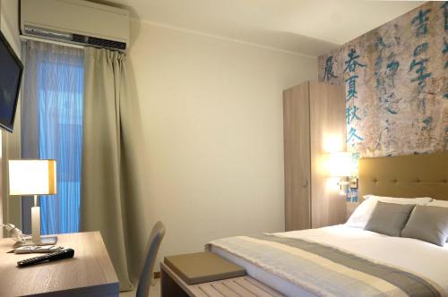 a hotel room with a bed and a desk and a window at Hotel Monaco in Caorle