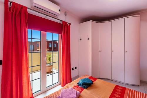 una camera da letto con tende rosse, un letto e una finestra di Casa Vacacional Golfin ad Arona