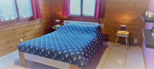 1 dormitorio con 1 cama azul en una habitación con ventanas en gitelecalibou, en Érezée