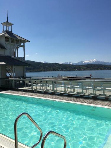 a swimming pool with a lighthouse in the background at See & You Ferienwohnung mit Hotelanbindung in Pörtschach am Wörthersee