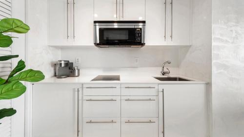 uma cozinha branca com um micro-ondas e um lavatório em Private Residence at W South Beach -811 em Miami Beach