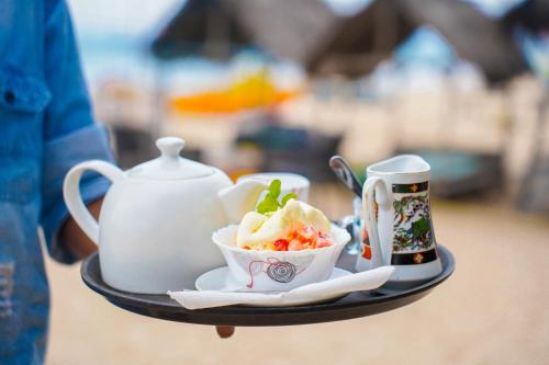 a tray with a tea pot and a bowl of food at The beach lovers nilaveli in Nilaveli