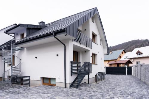 a white building with a black roof and stairs at Chalupa Martinček in Terchová