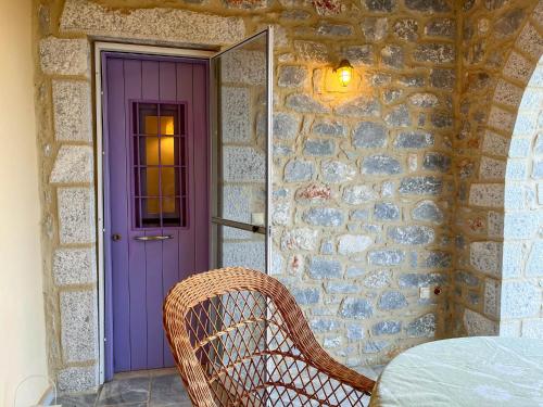 uma porta roxa com uma cadeira ao lado de uma parede de pedra em Mani family friendly, mountain house with parking em Oítilon