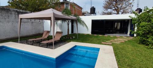 a backyard with a swimming pool and an umbrella at Casa Jardín Real in Temixco