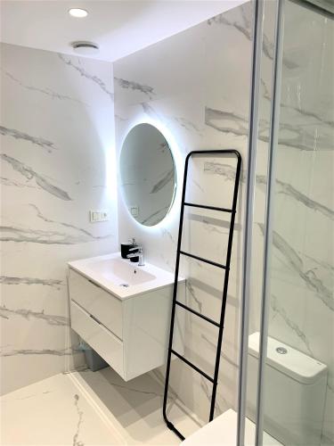 a white bathroom with a mirror and a sink at Malú Playa con Opción de Parking, in Gijón
