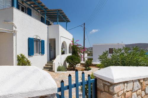 a white house with a blue fence in front of it at Summer House - Finikas Syros in Víssa