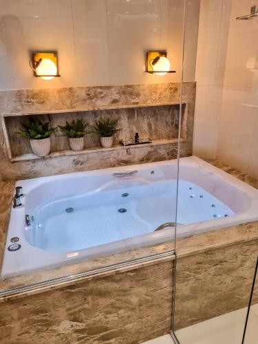 a large tub in a bathroom with two lights at Ananda Pousada in Pirenópolis