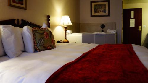 a hotel room with a large white bed with a red blanket at Hotel Grand Victorian in Branson