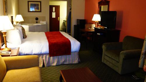 a hotel room with a bed and a couch and a chair at Hotel Grand Victorian in Branson