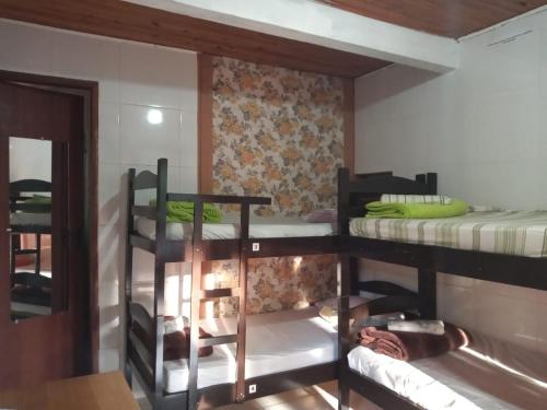 a room with three bunk beds and a mirror at Albergue Muzy in Sana