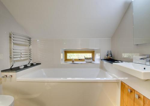 a white bathroom with a large tub and a sink at Derwen in Llanfihangel-geneuʼr-glyn