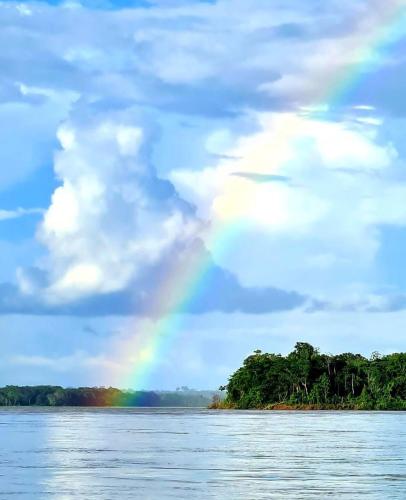 a rainbow in the sky over a body of water at Kanaq Hotel Tours in Leticia