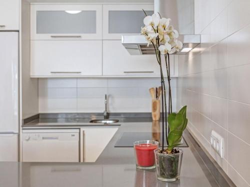 a kitchen with white cabinets and a vase with white flowers at Es Comtat 1 Muro in Muro