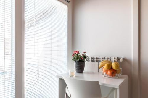 a table with a bowl of fruit on it next to a window at B&B Bianco E Blu in Marina di Ragusa