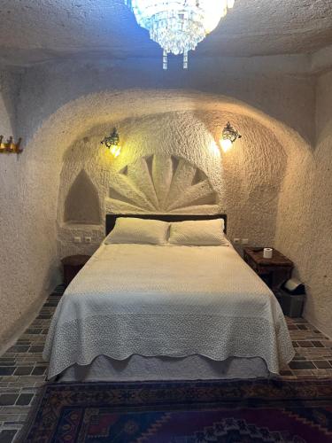 a bedroom with a large bed in a room with a chandelier at Uchisar Cave House in Uchisar