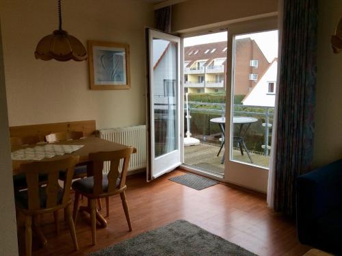a dining room with a table and a balcony at Haus Strandgang, Whg 5 in Kellenhusen