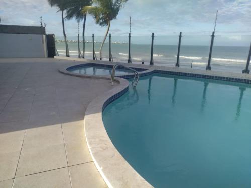 uma piscina com a praia ao fundo em Apartamento Pé Na Areia - Praia do Bessa - PB em João Pessoa