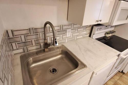 a stainless steel sink in a kitchen with white cabinets at Harvard Squares ONLY Tiny House on the Charles! in Cambridge