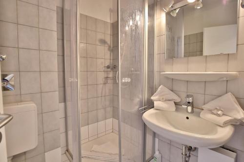 een witte badkamer met een wastafel en een douche bij Strandburg Strandburg Appartement 1 in Scharbeutz