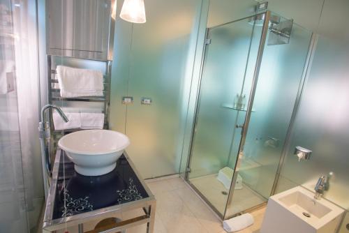 uma casa de banho com uma cabina de duche em vidro e um lavatório. em Hotel iDesign em San Marino
