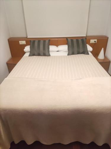 1 cama blanca grande con 2 almohadas en Piso acogedor con Parking, en Vigo