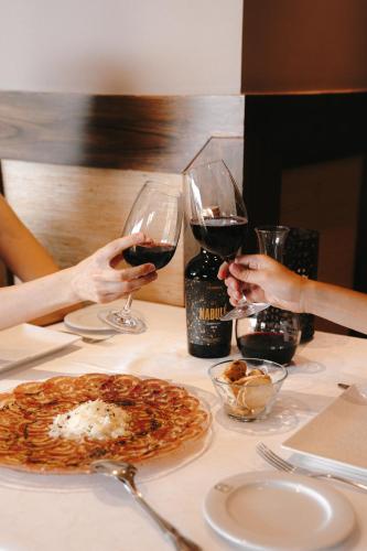 two people holding glasses of wine at a table with a pizza at Hotel Spa Balfagon in Cantavieja