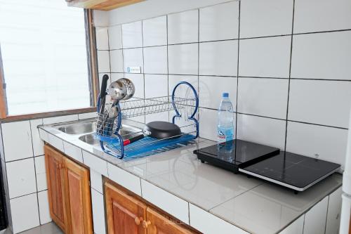 a kitchen counter with a dish rack and a sink at L'IMMEUBLE QUEEN M.N.M in Douala
