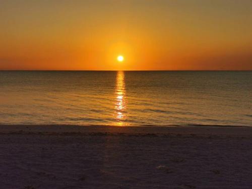 a sunset on the beach with the sun setting over the ocean at La Casa en Celestun in Celestún