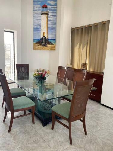 a dining room with a glass table with chairs and a lighthouse at La Casa en Celestun in Celestún