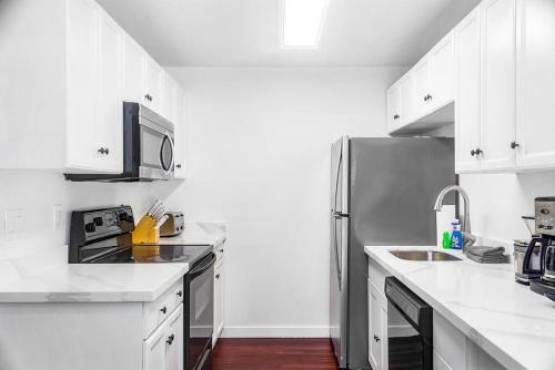 La cuisine est équipée de placards blancs et d'un réfrigérateur en acier inoxydable. dans l'établissement Seattle Cloud 2BR Prime Location, à Seattle