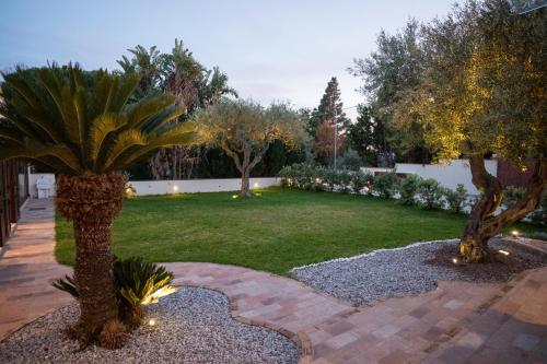 a garden with two palm trees and a lawn at B&B La Manica in Milazzo