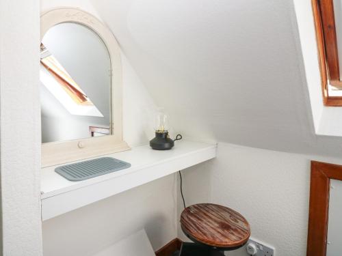a small bathroom with a mirror and a stool at Shell Cottage in Peterhead