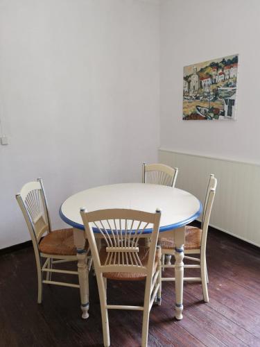 una mesa y sillas con una mesa blanca y una pintura en T2 petite terrasse coeur de ville, en Prats-de-Mollo-la-Preste