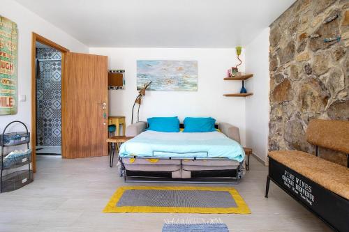 a bedroom with a bed and a stone wall at Estúdio Azul in Moledo
