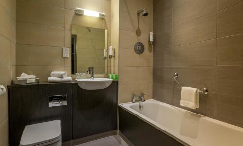 a bathroom with a tub and a sink and a toilet at Maldron Hotel Shandon Cork City in Cork