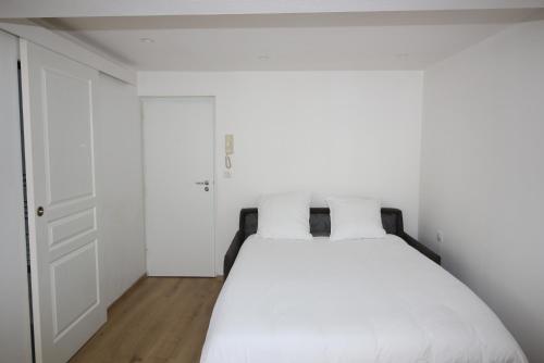 1 dormitorio con 1 cama blanca y 2 almohadas blancas en Moulins Studio cœur de ville de Saint Dizier, en Saint-Dizier