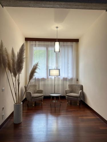 a living room with two chairs and a table and a window at Villa Belvedere di Popiglio in Popiglio