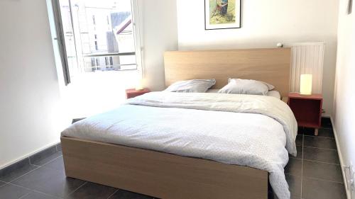 een slaapkamer met een groot bed met witte lakens en een raam bij Marguerite-Gap Centre in Gap